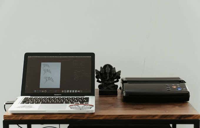 プリンター付きの机の上の Mac ラップトップ