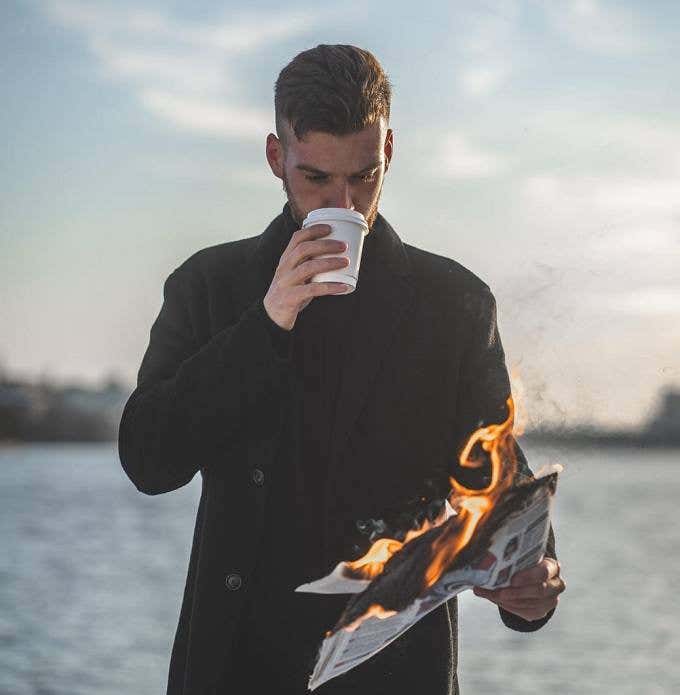 Hombre leyendo un periódico que está en llamas