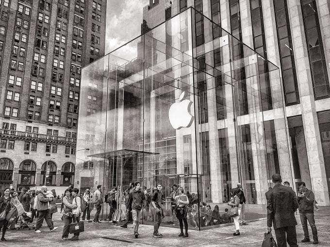 Personas de pie fuera de una Apple Store de cristal