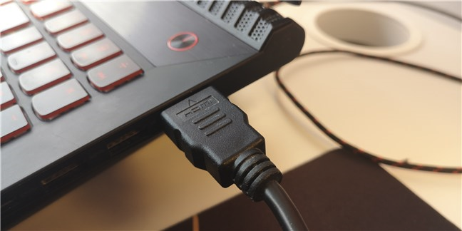 Un cable HDMI conectado al puerto HDMI de una computadora portátil