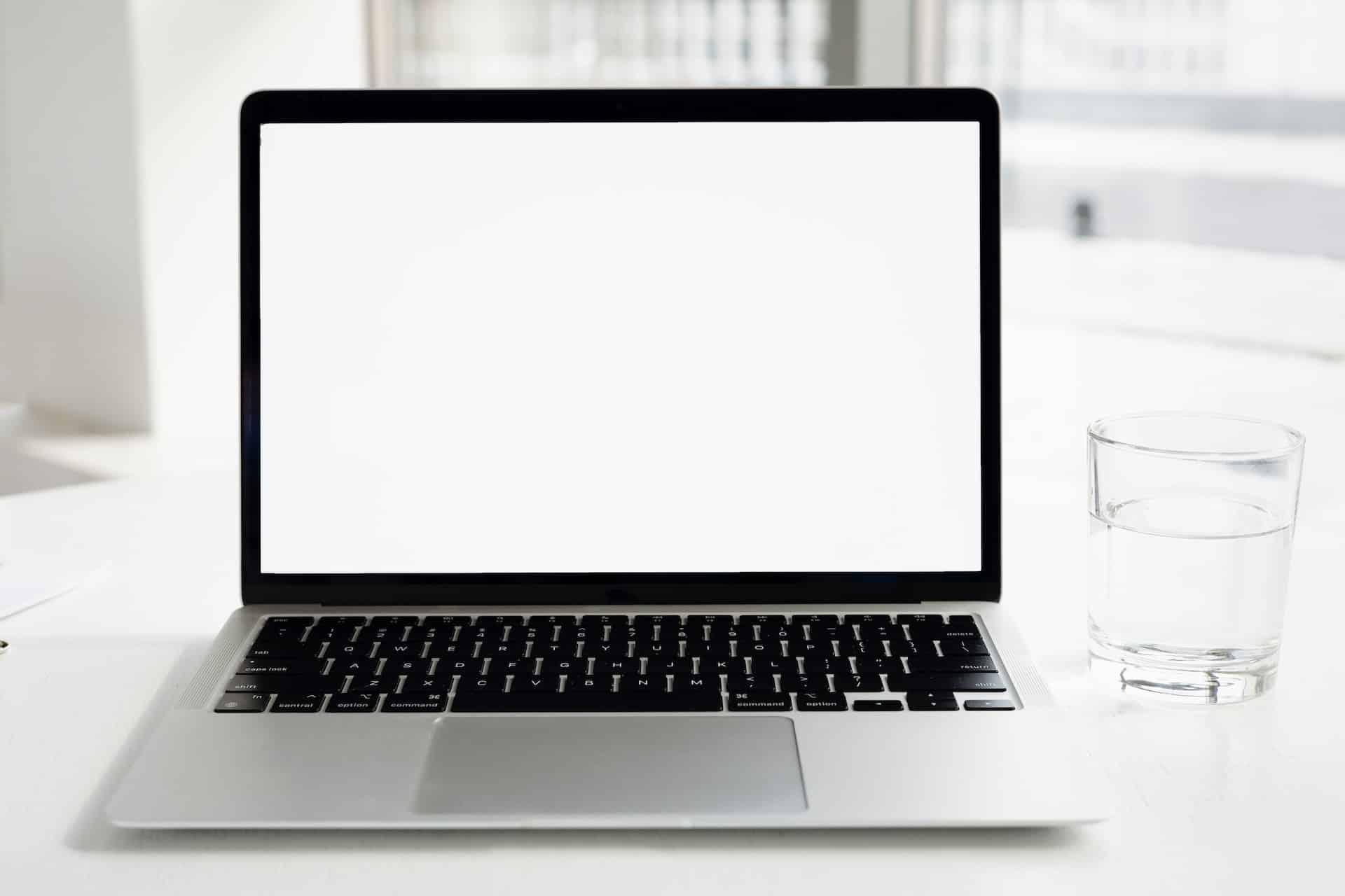 Laptop y vaso de agua