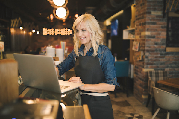 persona navegando por diseños de sitios web antiguos en una laptop en un restaurante